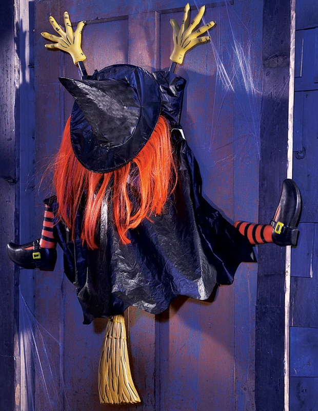 A decorative witch on splattered on a front door, as if she crashed into the door off her broom